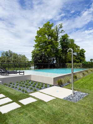 A swimming pool with a metal deck, surrounded by grass and a hedge. - Ficus Suite (Ca' Nani)