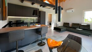 Une cuisine moderne avec un îlot central, un coin repas doté d’une table en verre et un salon avec un canapé.