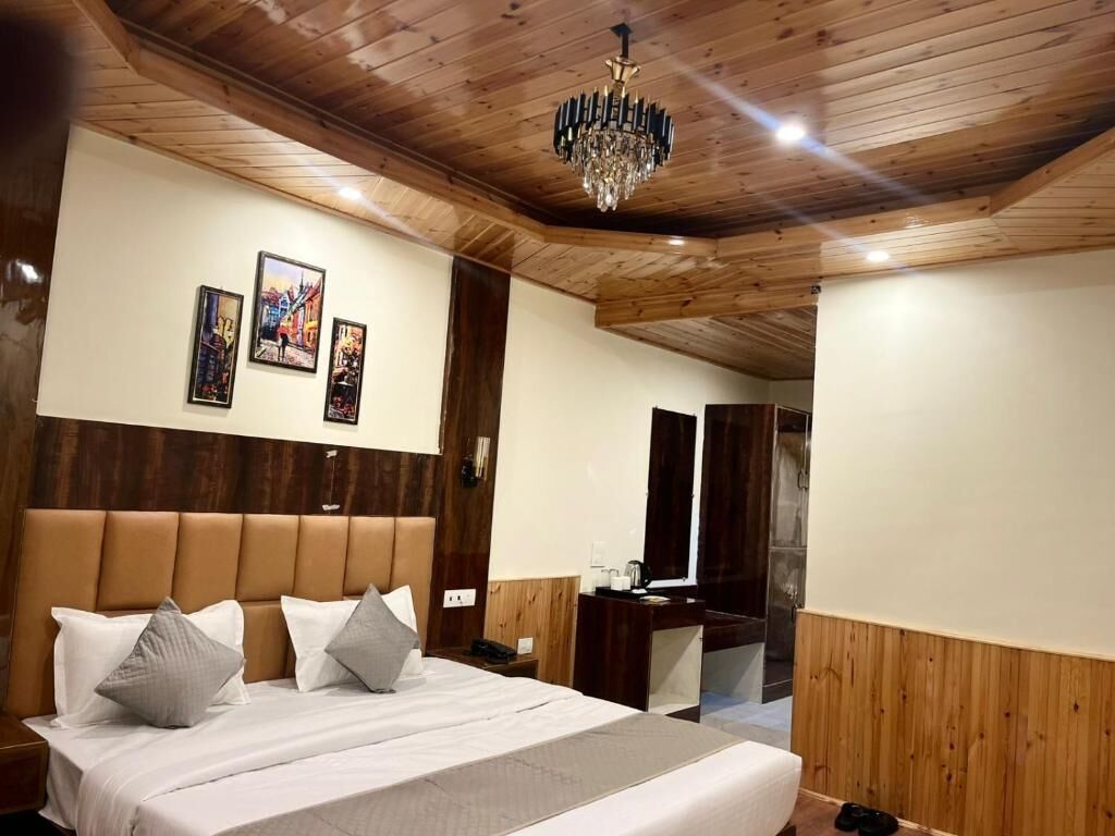 Ein Schlafzimmer mit Holzboden, einem großen Bett mit Kissen, einer Chandelierleuchtre und drei gerahmten Bildern an der Wand.