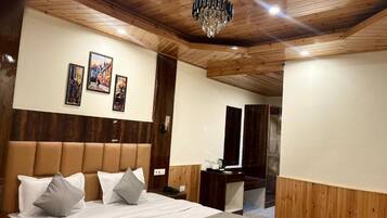 Ein Schlafzimmer mit Holzboden, einem großen Bett mit Kissen, einer Chandelierleuchtre und drei gerahmten Bildern an der Wand.
