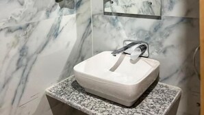 Een badkamer met een wit marmeren wastafel, een spiegel en een handdoekhouder.