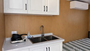 A compact kitchen with a double sink, a stove, and white cabinets.