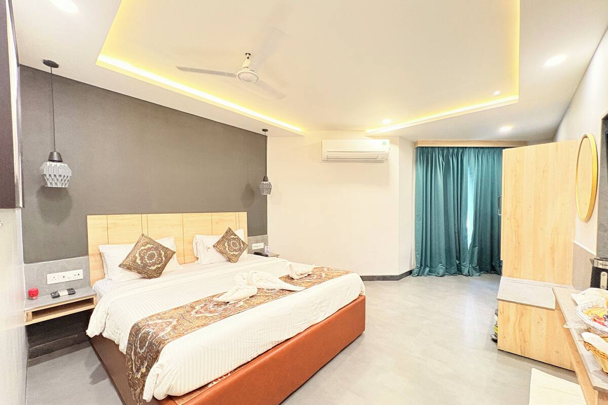 A modern hotel room with a large bed, a ceiling fan, an air conditioning unit, a vanity with a mirror, and a wardrobe.