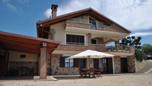 Ein zweistöckiges Haus mit Balkon, Außenbereich zum Sitzen und einer Steinmauer.