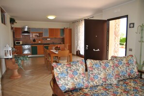 Ein kompakter Wohnbereich mit Küchenzeile, Essbereich und einer blumengedeckten Couch.