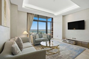 A modern living room with a sofa, a coffee table, and a TV mounted on the wall. - Stunning 2 Bedroom in Palm with private beach (Dubai)