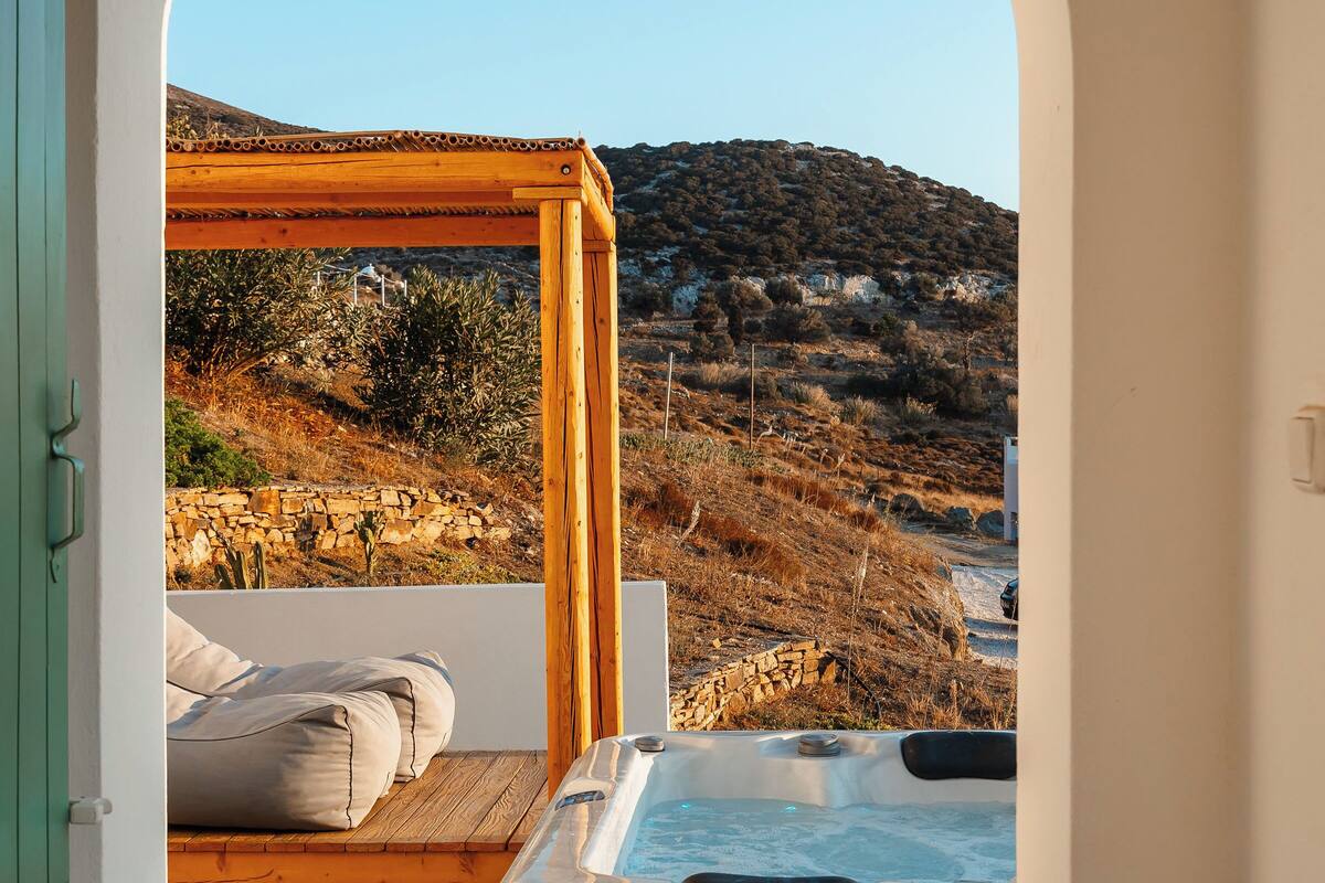A hot tub in a covered outdoor area with a view of a hillside.