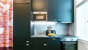 Een moderne keuken met donkere kastjes, een ingebouwde oven en een raam.