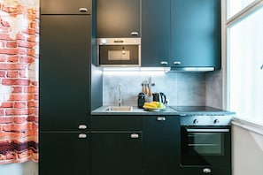 A modern kitchen with dark cabinetry, a built-in oven, and a window. - 6 min walk to metro - 3 stops to city center (Wien)