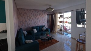A modern living room with a sofa, a coffee table, and a TV. - Charming 2-Bedroom Apartment with Stunning Views in Santiago (Santiago de los Caballeros)