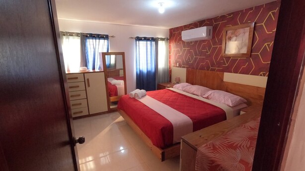 A bedroom with a bed, a wardrobe, a mirror, and an air conditioning unit. - Charming 2-Bedroom Apartment with Stunning Views in Santiago (Santiago de los Caballeros)