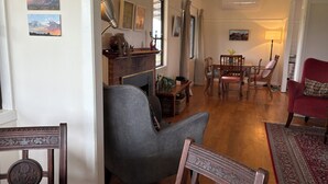 A cozy living room with a fireplace, dining area, and a red armchair. - Mountain-view farmhouse farmstay on the Capertee Valley Bird Trail (Bogee)