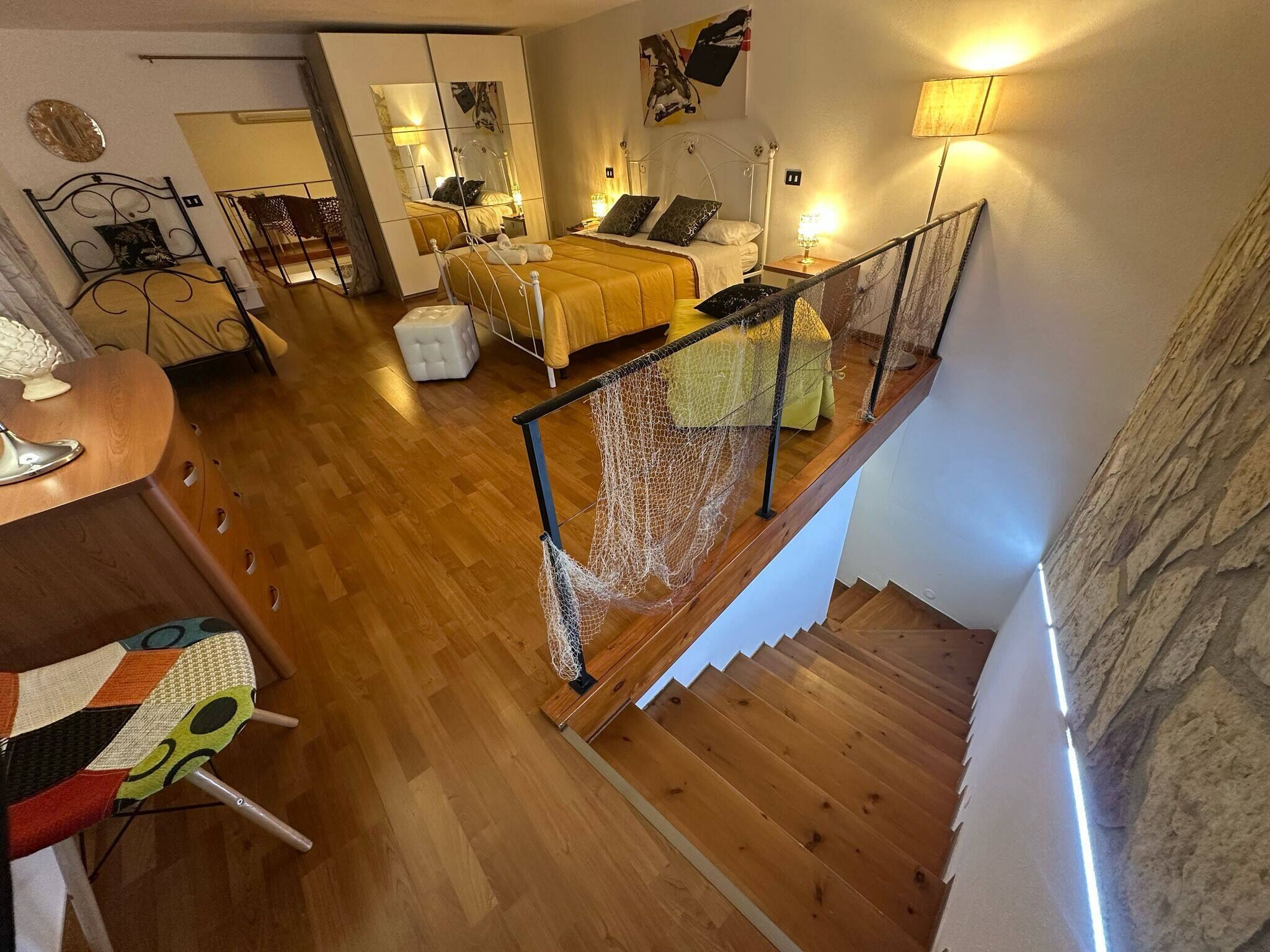 Un'ampia stanza con un letto grande, una scala in legno e vista sull'area soggiorno.