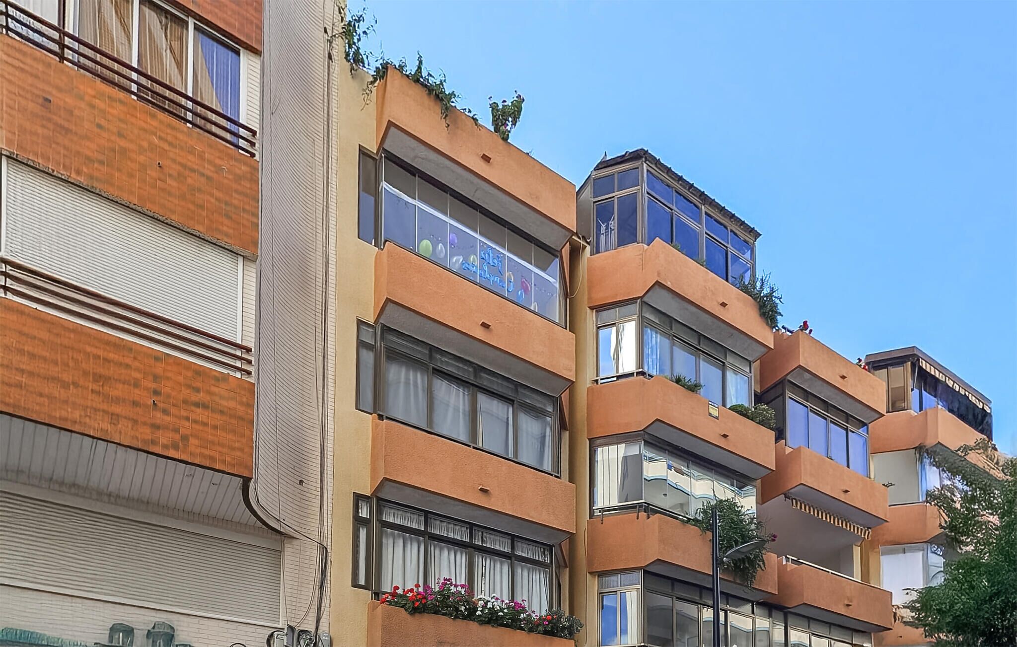 Um edifício residencial com várias andares, varandas, janelas amplas e fachada de tijolos.