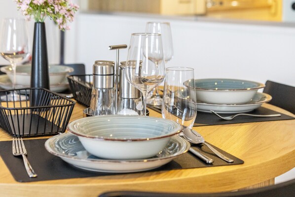 A dining table set with plates, glasses, cutlery, and a vase with flowers.