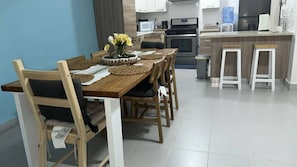 A modern kitchen with a dining area, featuring a wooden table with chairs, a vase with flowers, and a kitchen counter with appliances. - Beautiful 2R2B apartment in Playa Bibijagua, Punta Cana (Punta Cana)
