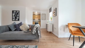 Una sala moderna con un sofá gris, una mesita y una zona de comedor con una silla.