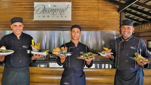 Drei Kellner in einem Restaurant tragen Teller mit Speisen.