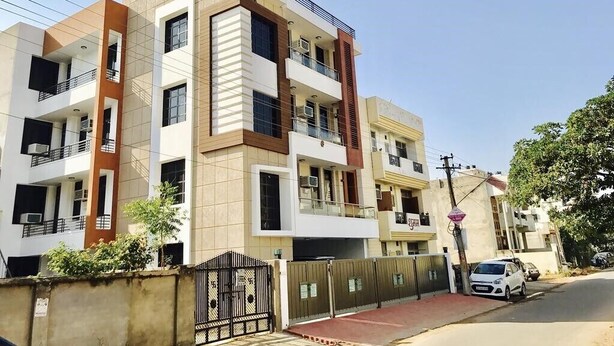 A multi-story residential building with balconies, a gated entrance, and a parked car. - BluO 1BHK Jaipur Terrace Garden Lift (Jaipur)