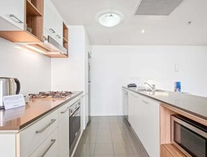 A modern kitchen with white cabinets, a stainless steel range hood, and a built-in oven. - High-Floor 1BR City Escape with Balcony Views (Brisbane)