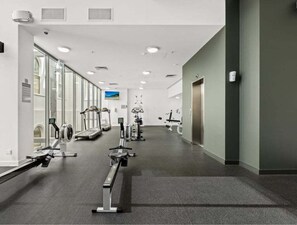 A modern gym with cardio machines, weight stations, and a large mirror. - High-Floor 1BR City Escape with Balcony Views (Brisbane)