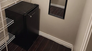 A small, enclosed room with a black refrigerator, white shelving units, and a mirror on the wall. - Room-private Master Room in a Quiet Hous (Woodstock)