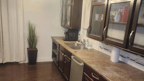 A kitchen with dark wooden cabinets, a granite countertop, a built-in microwave, and a dishwasher. - Room-private Master Room in a Quiet Hous (Woodstock)