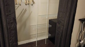 A walk-in closet with a metal shelving unit, wooden hangers, and a black chair. - Room-private Master Room in a Quiet Hous (Woodstock)