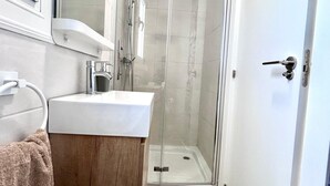 Une salle de bain moderne avec une douche à parois de verre, un lavabo blanc et un porte-serviettes.