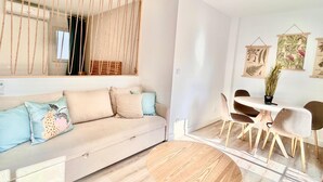 Un salon moderne avec un canapé, une table ronde en bois et un coin repas avec des chaises.