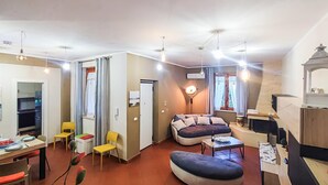 A compact living space with a kitchenette, a sofa, a dining table, and a small TV. - Stunning home in Altavilla Milicia (Altavilla Milicia)