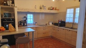 Una cucina con forno a microonde, forno, lavandino e diversi elettrodomestici. Sono presenti armadietti, un piano di lavoro e una finestra.