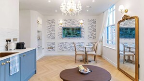 Een moderne keuken met een blauwe kast, een kroonluchter, een eettafel met stoelen en een grote spiegel.