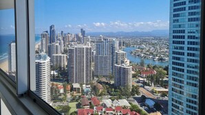 A high-rise building with a view of a cityscape, including various buildings and a body of water. - Level 38 Ocean-View Apartment, Surfers Paradise (Surfers Paradise)