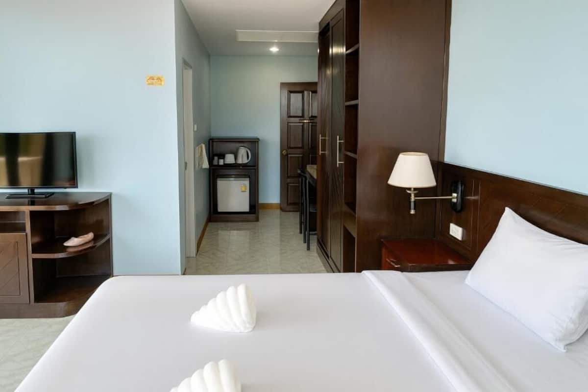 Une chambre d’hôtel équipée d’un lit, d’une télévision, d’un bureau, d’une armoire et d’une petite kitchenette.
