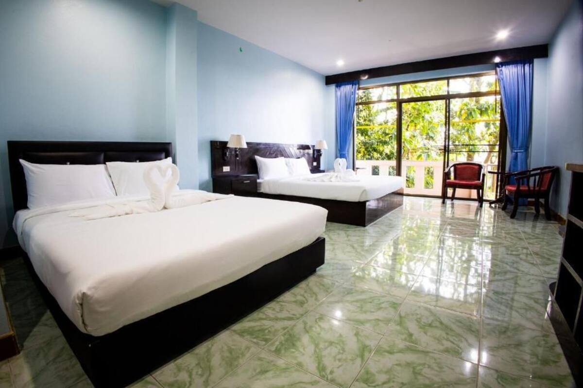 Une chambre d’hôtel avec deux lits, un balcon avec vue et un coin salon.