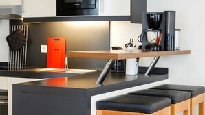 A modern kitchen with a central island, a coffee machine, and bar stools. - 5-Star Comfort Holiday Home Jümmers – 'Pidder', Prime Location by the Wadden Sea National Park (Wangerland-Horumersiel)