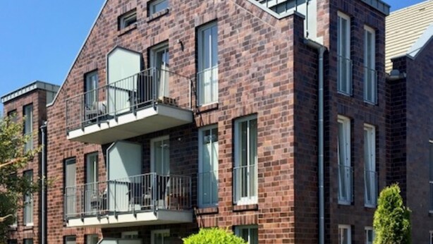 A multi-story brick building with balconies, large windows, and a clear sky. - 5-Star Comfort Holiday Home Jümmers – 'Pidder', Prime Location by the Wadden Sea National Park (Wangerland-Horumersiel)