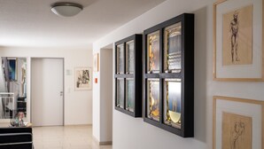A hallway with framed artwork on the walls, a door, and a black cart. - 5-Star Comfort Holiday Home Jümmers – 'Pidder', Prime Location by the Wadden Sea National Park (Wangerland-Horumersiel)
