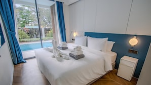 Ett hotellrum med en stor säng, ett sängbord, ett litet bord och utsikt över en swimmingpool.