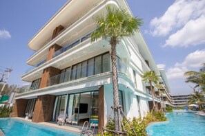 Ein modernes Hotel mit Pool, mehreren Balkonen und einem tropischen Garten.