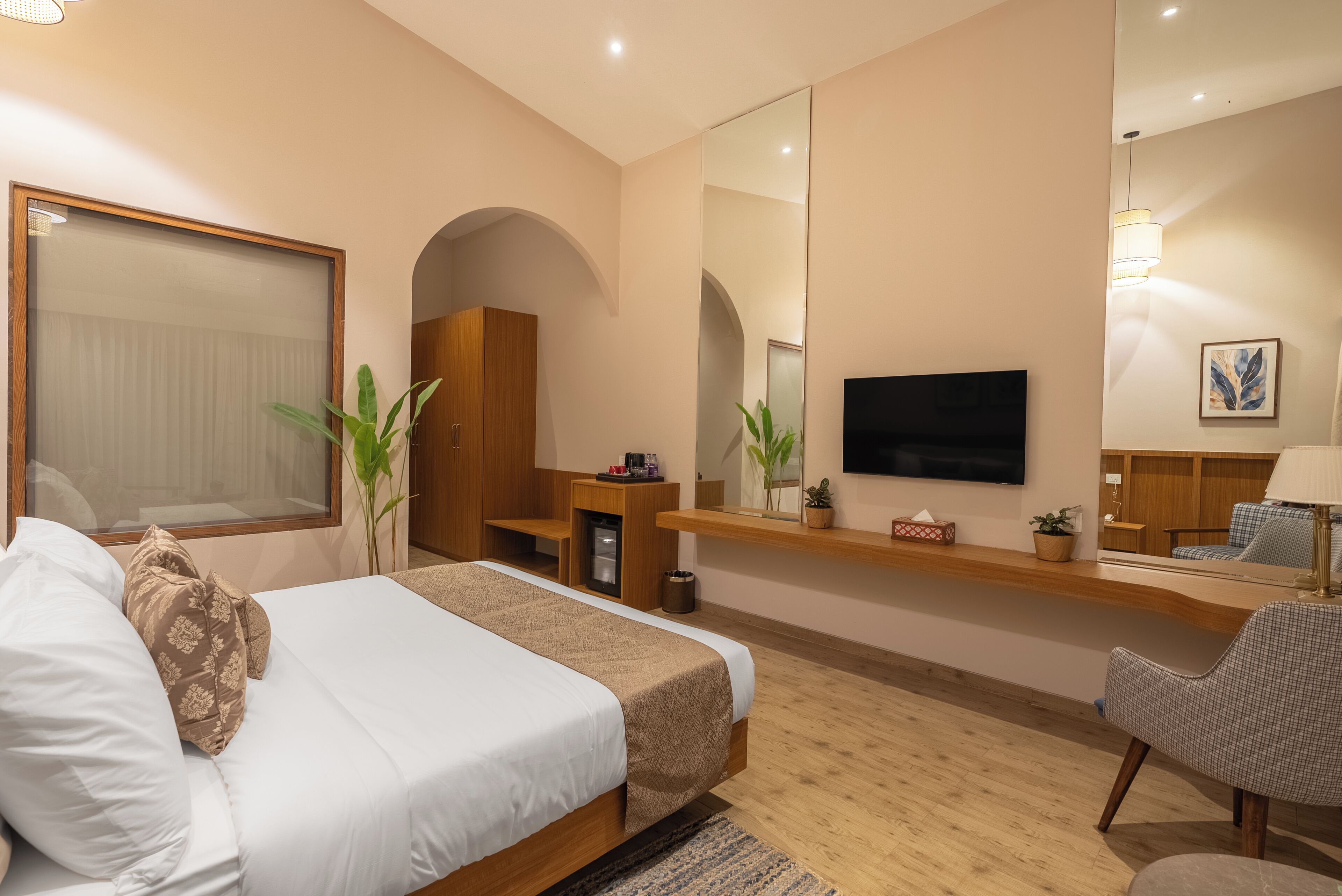Una habitación de hotel moderna con una cama grande, televisor, escritorio y zona de estar.
