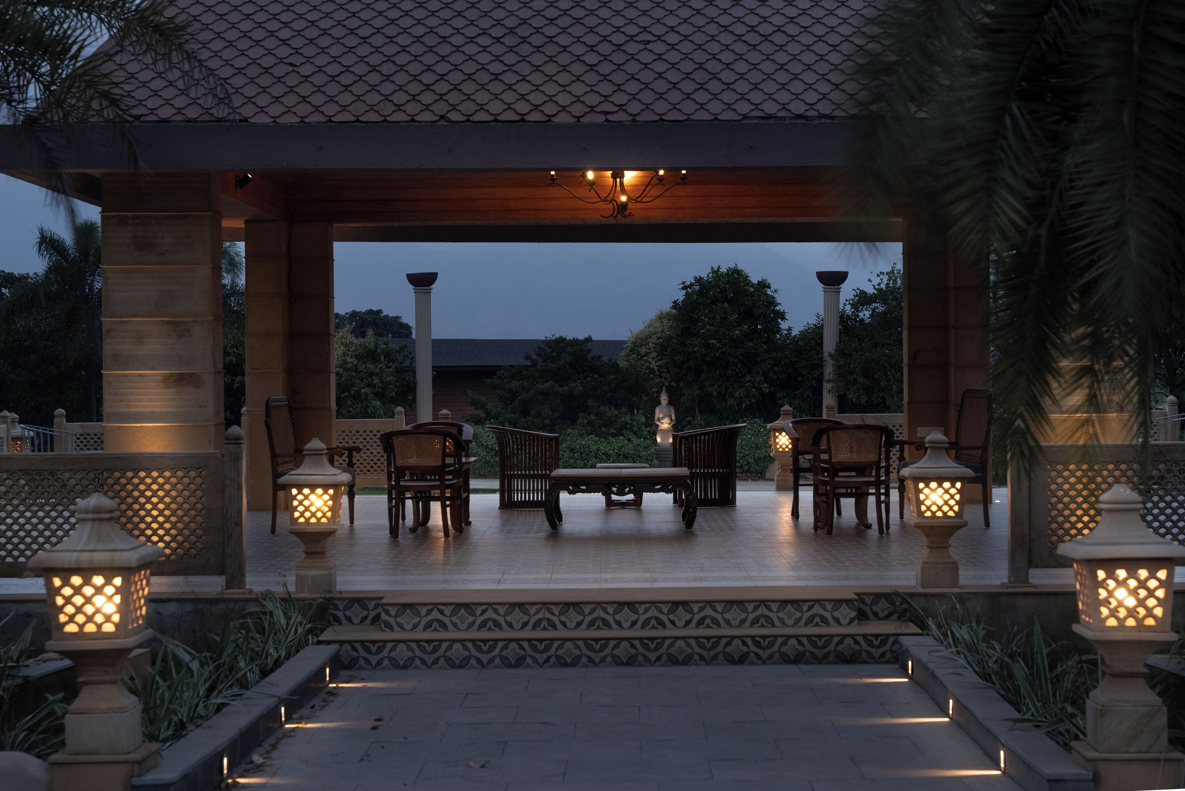 An outdoor patio with a wooden table and chairs, surrounded by decorative lanterns and a patterned floor.