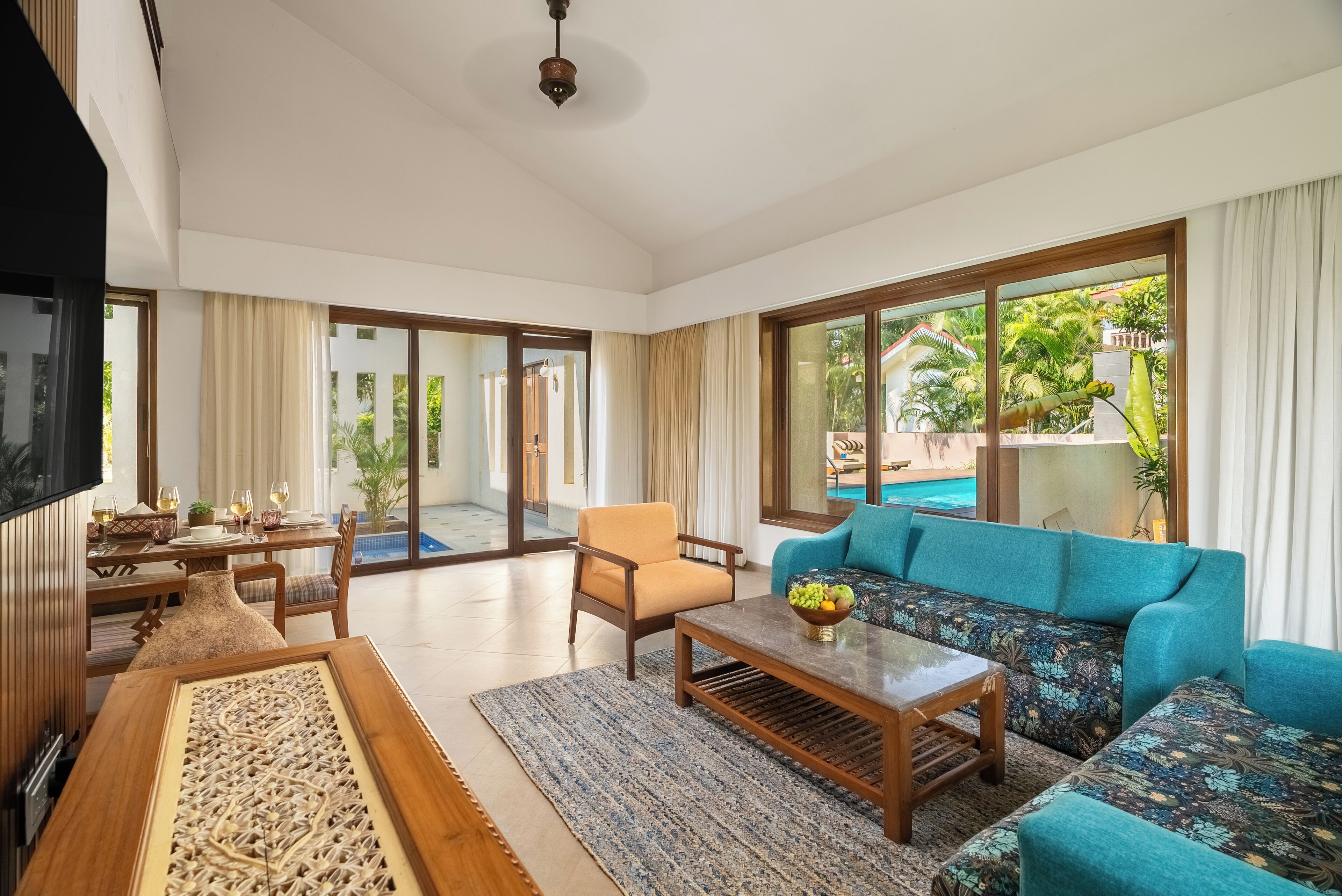 A spacious living room with a sofa, armchair, coffee table, and a TV.
