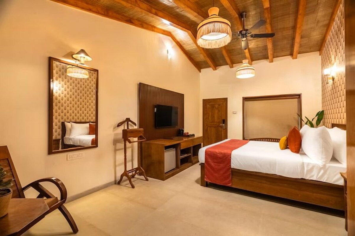A bedroom with a bed, a desk, a television, and a ceiling fan.
