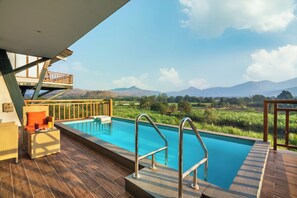 Una piscina al aire libre, sombrillas, sillones reclinables de piscina