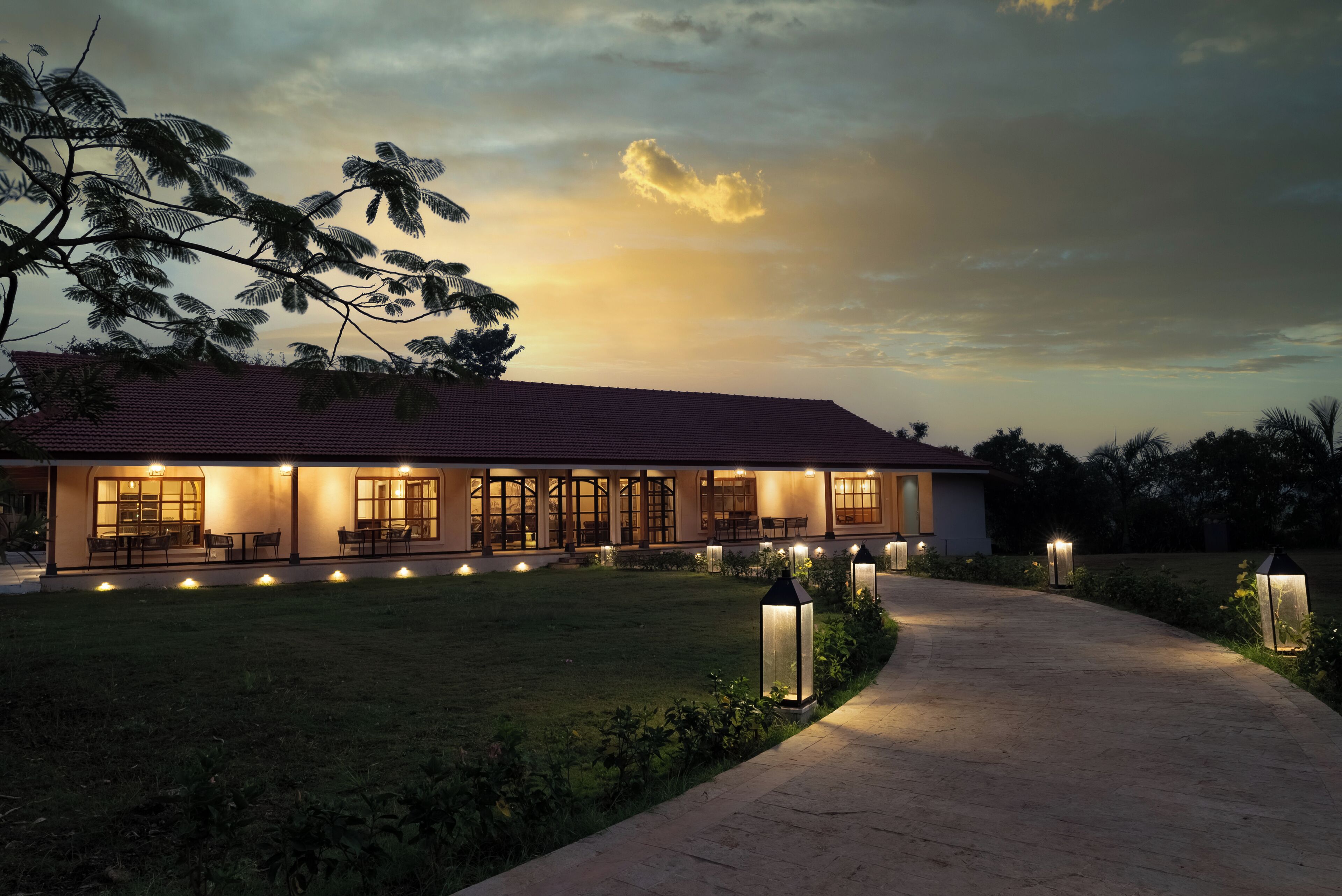 A modern house with a well-lit exterior, a paved driveway, and a landscaped garden.