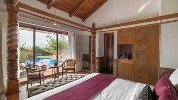 Une chambre dotée d’un grand lit, de poutres apparentes en bois au plafond, d’une vue sur l’extérieur, d’un coin salon avec une piscine et d’une armoire.