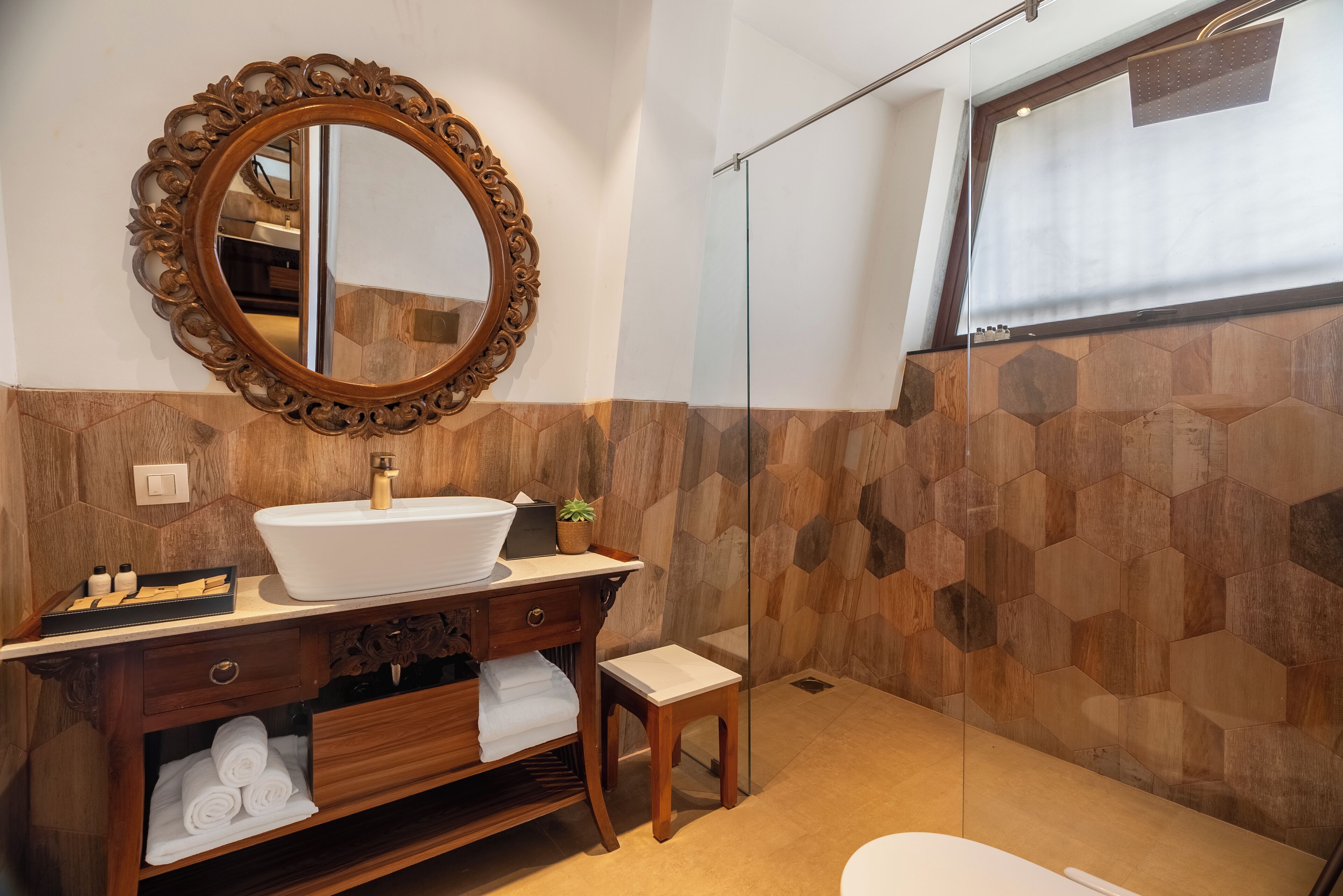 Un baño con tocador de madera, un espejo grande, un lavamanos blanco y una zona de ducha.
