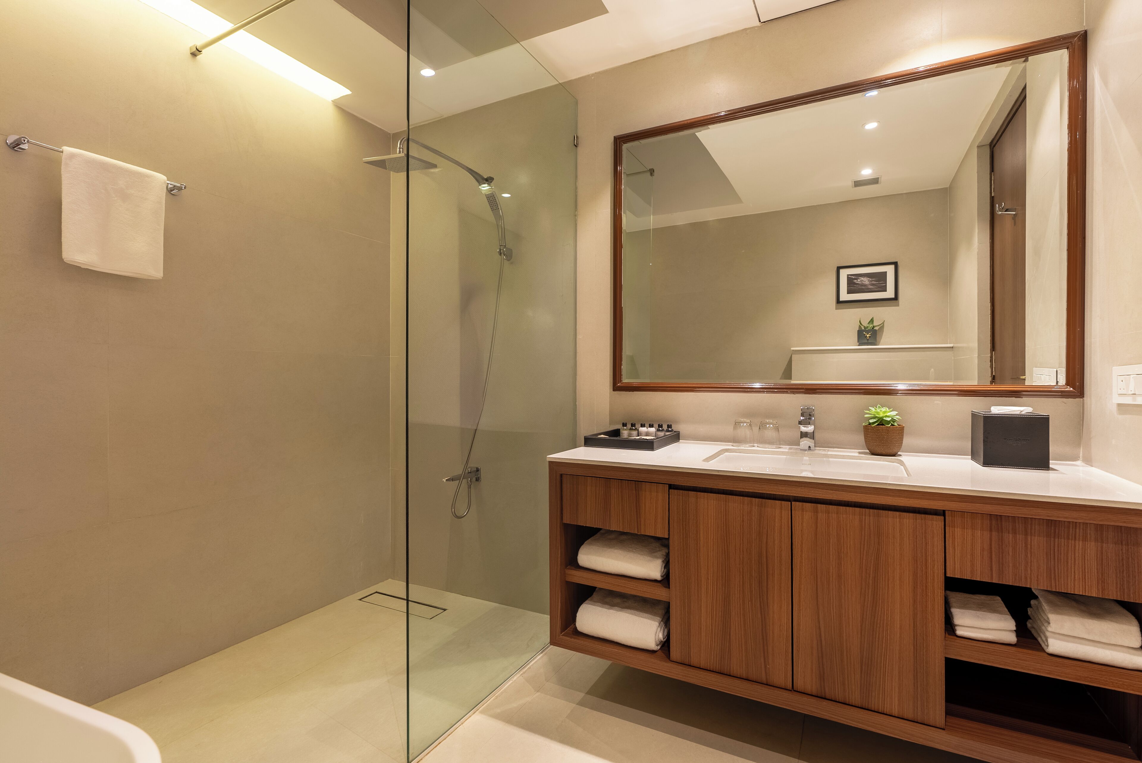 A modern bathroom with a glass shower enclosure, wooden vanity, and a large mirror.